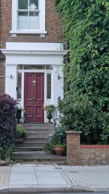 The image shows the entrance to a residential property with a rich, reddish-purple front door set within a white-painted architectural frame featuring a decorative lintel and narrow side panels. The d